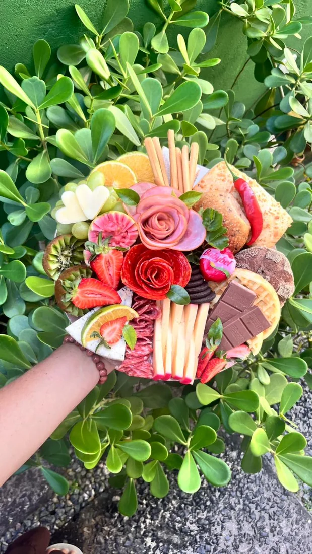 Arranjo delicado com flores, doces e folhagens.