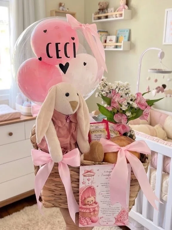 Cesta de maternidade com coelhinho, flores e balão rosa.